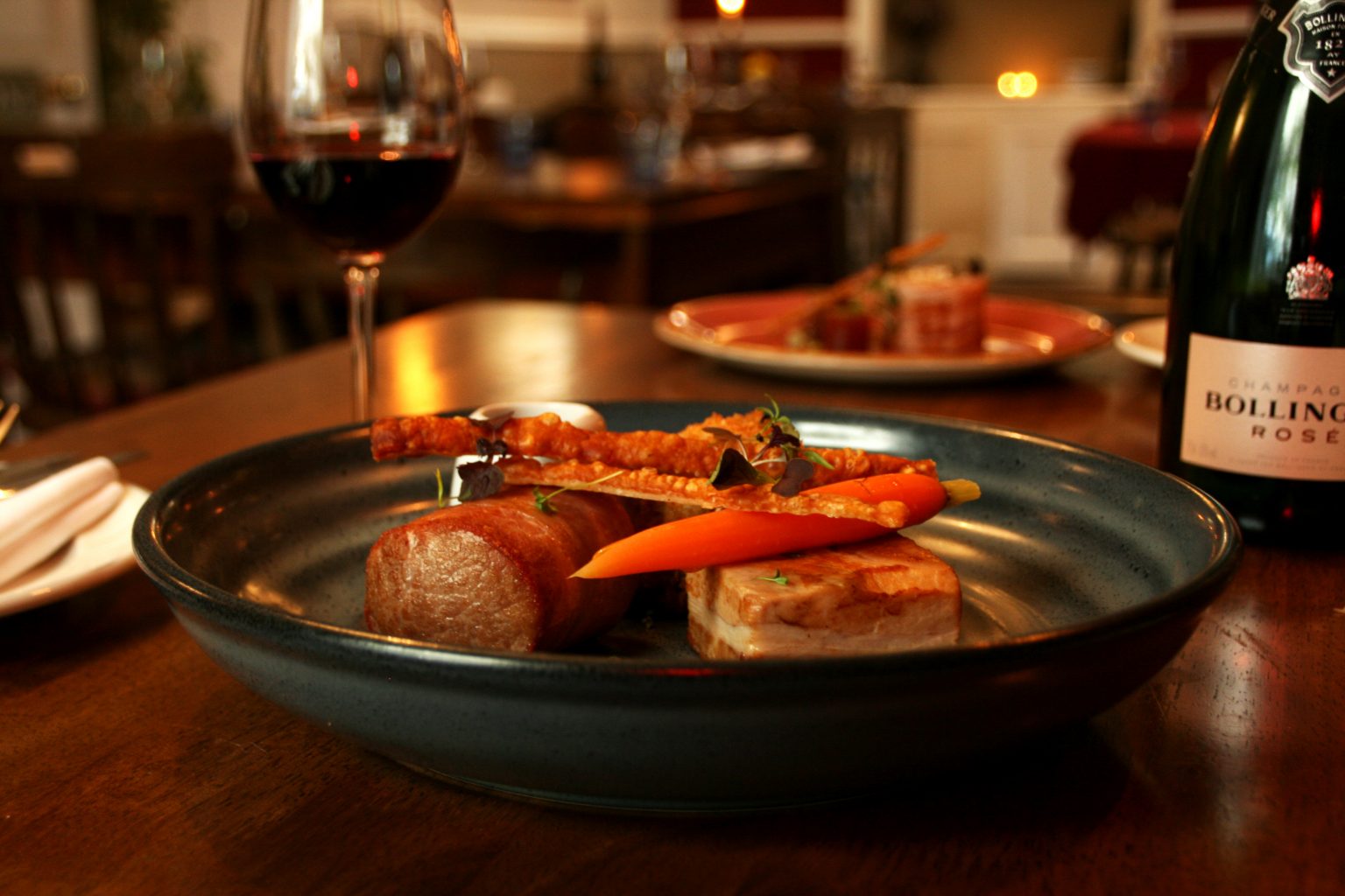 A plated dinner and a glass of red wine on a table at the Bruce Arms